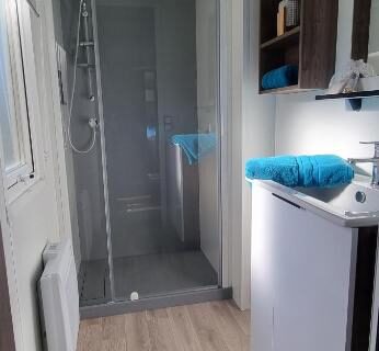 Salle d'eau avec douche vitrée et kitchenette dans le mobil-home Camping Les Oyats 4 Etoiles
