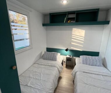 Chambre avec deux lits simples et fenêtre dans le Mobil-home Camping Oasis