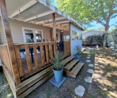 Terrasse en bois ombragée avec pots et escaliers du mobil-home Camping Siblu La Reserve
