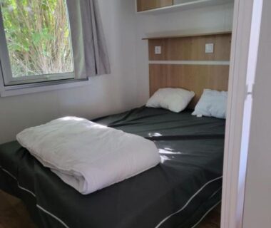 Chambre avec lit double rangements et fenêtre dans le Mobil home Céleste 6-8 personnes