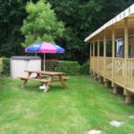 Terrasse en bois et table pique-nique avec parasol au Mobil home Céleste 6-8 personnes