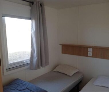 Chambre avec deux lits simples près de la fenêtre dans le mobil home Céleste 6-8 personnes