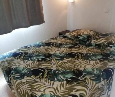 Chambre avec lit et couette à motif feuilles dans le mobil home Chez 118 Alain