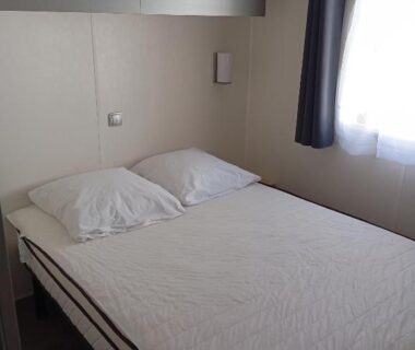 Chambre avec lit double placard mural et fenêtre dans le Mobil home Chrisali