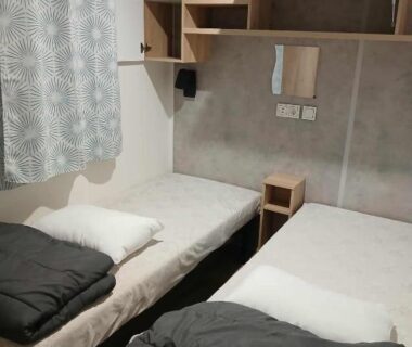 Chambre avec deux lits simples et rangements dans le mobil-home Camping Marisol