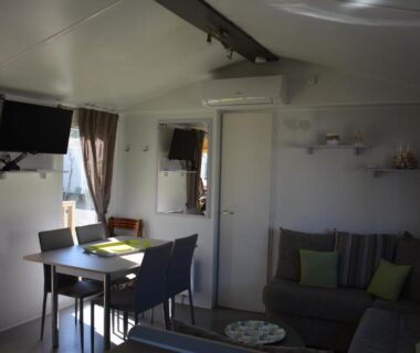 Intérieur avec coin repas canapé et télévision du mobil home MH-A004 au Camping LA CARABASSE