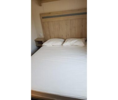 Chambre avec lit double et deux oreillers dans le mobil-home MH-A026 au Camping Le Lac des Rêves