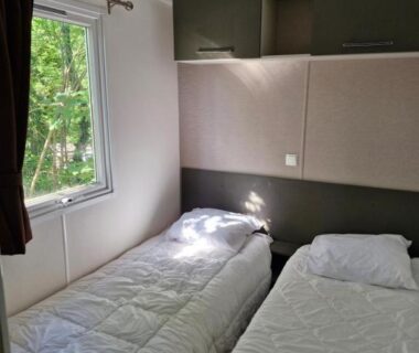 Chambre avec deux lits simples et fenêtre sur la verdure dans le Mobil home Côte d'Opale