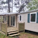 Terrasse en bois entourée d'arbres du Mobil home Côte d'Opale