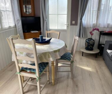Séjour avec table ronde chaises canapé et télévision dans le Mobil home Cristal