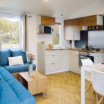 Séjour avec canapé bleu et coin cuisine dans le mobil-home Dan Dom