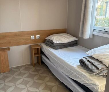 Chambre avec lit, étagères et fenêtre dans le mobil home Domaine de Kerlann