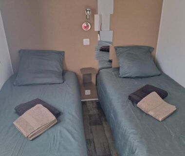 Chambre avec deux lits simples et serviettes dans le Mobil home Domaine de la Forge