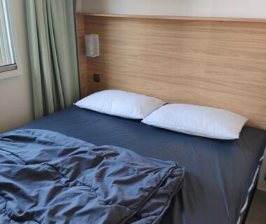 Chambre avec lit double et tête de lit en bois dans le mobil home Houlgate