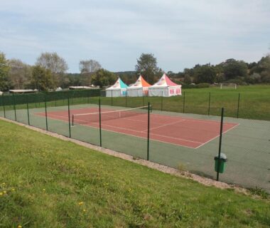 Terrain de tennis entouré de pelouse et kiosques colorés au Mobil home Houlgate