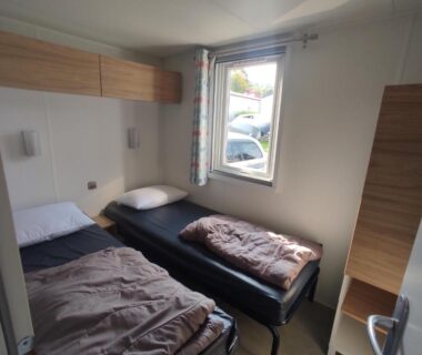 Chambre avec deux lits et fenêtre donnant sur l'extérieur dans le Mobil home Houlgate