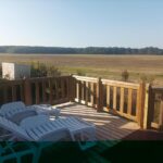 Terrasse en bois avec chaises longues et vue sur campagne du Mobil home Le Galland de Dugny