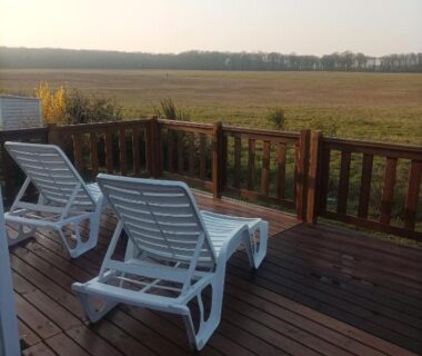 Terrasse en bois avec deux transats donnant sur les champs du Mobil home Le Galland de Dugny