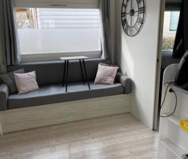 Coin salon avec banquette et horloge dans le mobil home Le petit Paradis