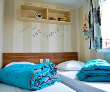 Chambre avec deux lits et couettes turquoises dans le mobil-home Mick et Stefie