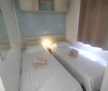 Chambre avec deux lits simples et serviettes dans le mobil home Mon Oasis de rêves Les Palmiers