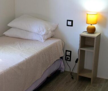 Chambre intérieure avec lit, table de chevet et lampe dans le mobil-home Narbonne-Plage