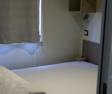 Chambre avec lit et étagères dans le mobil-home Narbonne-Plage
