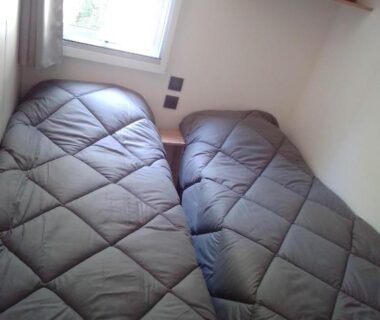 Chambre avec deux lits simples et fenêtre dans le mobil home Neuf 6 places Climatisé