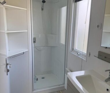 Salle d'eau avec douche vitrée lavabo et fenêtre dans le mobil home Ouistreham
