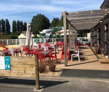Terrasse extérieure avec chaises rouges et parasols au Mobil-home Ouistreham