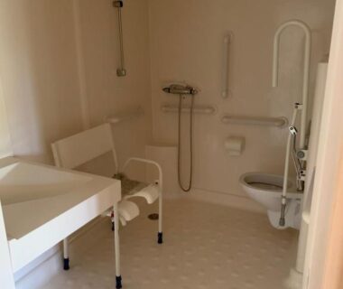 Salle de bain accessible avec siège et barres d'appui dans le Mobil-home PMR