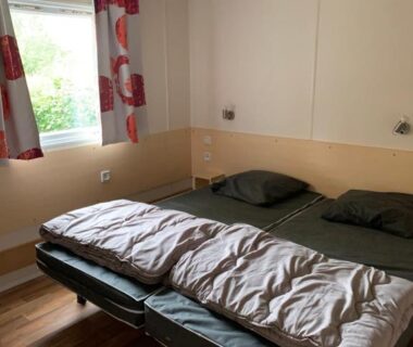 Intérieur avec deux lits fenêtre et rideaux dans le mobil-home PMR