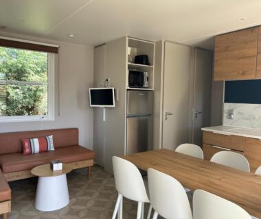 Séjour avec coin repas canapé et kitchenette dans le Mobil home PREMIUM 35m2 3 chambres 6 personnes