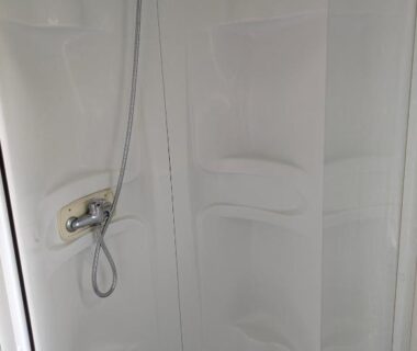 Salle d'eau avec cabine de douche blanche dans le mobil home Phoenix 6 places