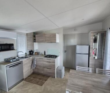 Intérieur cuisine équipée et coin repas dans le Mobil-home Premium 6 couchages Camping La Marine Homair