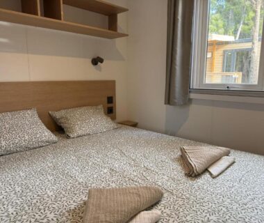 Chambre intérieure avec lit double et serviettes dans le Mobil home Premium 6p