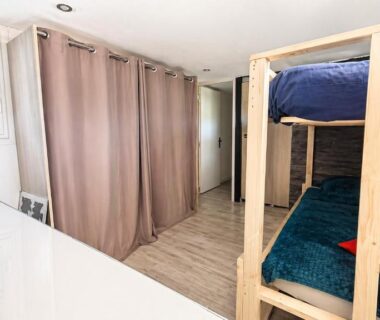 Intérieur avec lits superposés et rideau séparateur dans le Mobil-home Premium Piscine BBQ et Home Cinéma