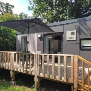 Terrasse extérieure avec parasol et chaises du mobil home TAOS Luxe H20 au Camping de Lanniron