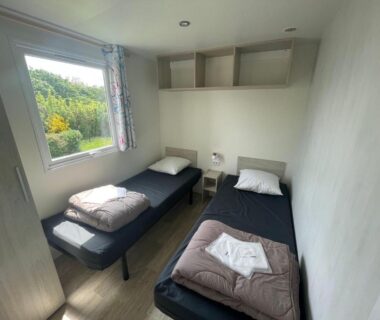 Chambre avec deux lits simples et fenêtre dans le mobil home XL 6 personnes au Camping La Pommeraie de l’Océan