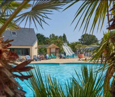 Piscine extérieure avec toboggan et palmiers au Mobil home XL 6 personnes du Camping 4 étoiles La Pommeraie de l'Océan
