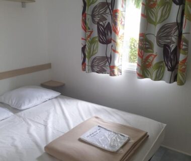 Chambre avec lit et rideaux dans le mobil home à Boofzheim EUROPA PARK et RULANTICA