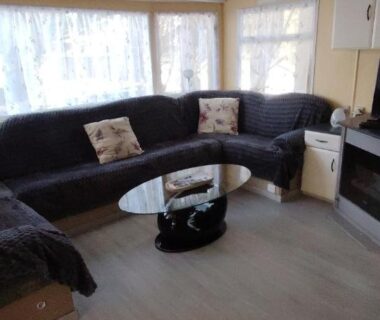Salon avec canapé incurvé et télévision dans le mobil-home à Hourtin terrasse piscine proche lac et océan