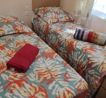 Chambre avec deux lits et serviettes dans le mobil-home à Hourtin