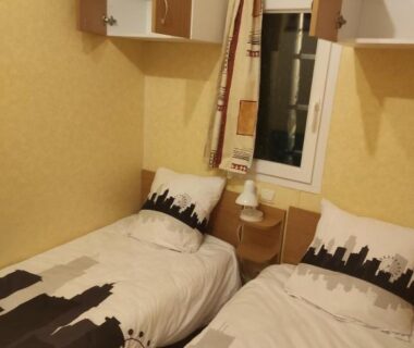 Chambre avec deux lits fenêtre et rangements dans le Mobil home agreable et fonctionnel