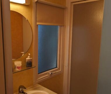 Salle de bain avec lavabo miroir fenêtre et cabine de douche dans le Mobil home agreable et fonctionnel