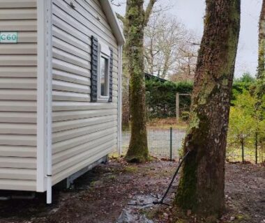Emplacement boueux avec mobil-home et arbres du Mobil-home alex