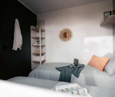 Chambre intérieure avec deux lits et coussin orange dans le mobil home API-1-52-2257