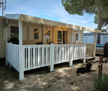 Terrasse en bois ombragée devant mobil-home et chien dans le Mobil-home au Camping familial 4 étoiles Les Sables d'Or