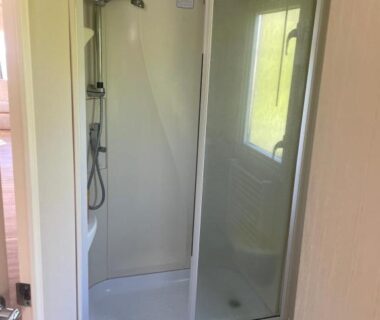 Salle de douche avec cabine et fenêtre dans le mobil home au bord de la mer