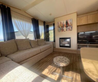 Salon avec baie vitrée et vue mer dans le mobil home camping de la falaise à Equihen-Plage